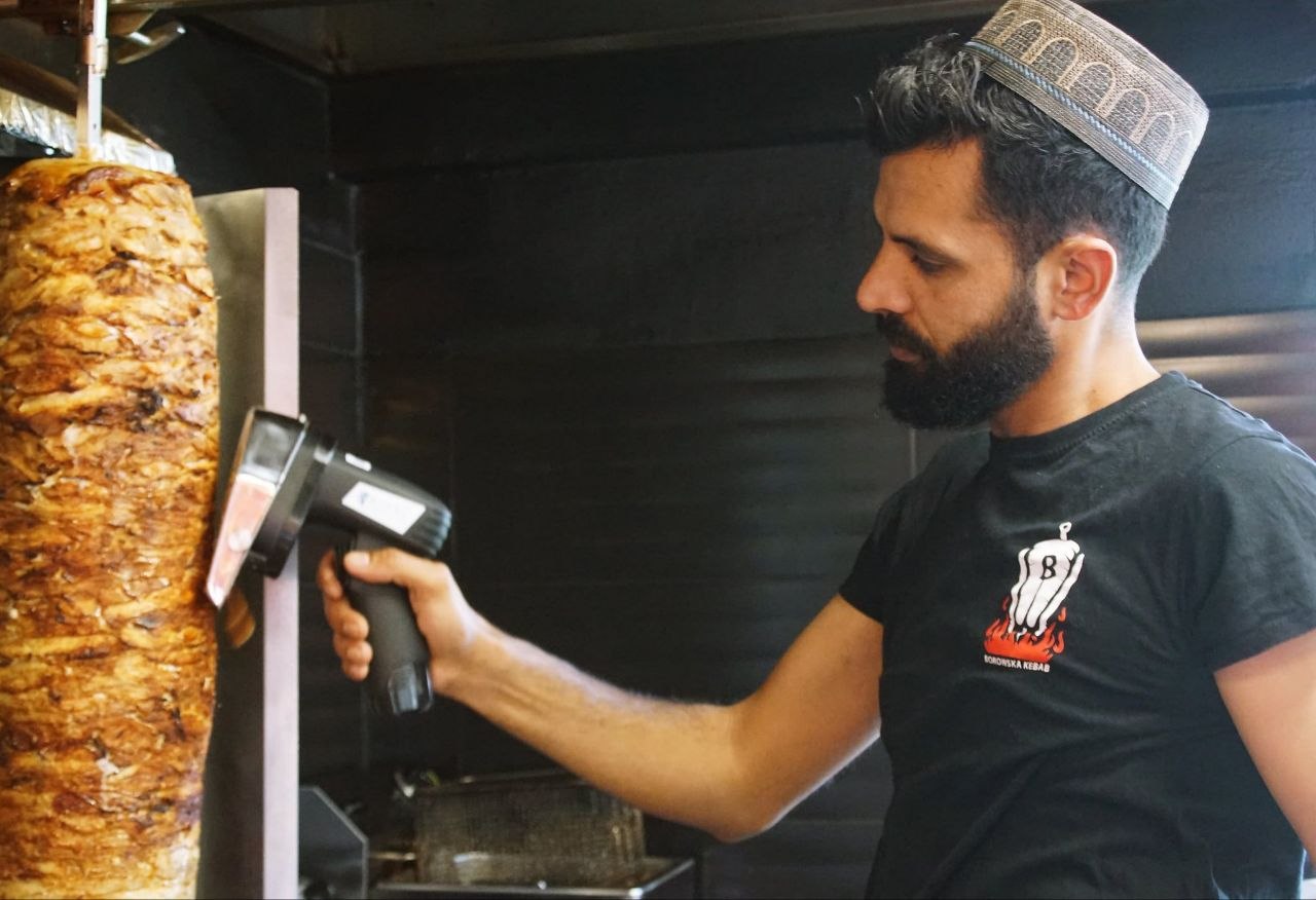 Pracownik dokładnie kroi mięso na kebab